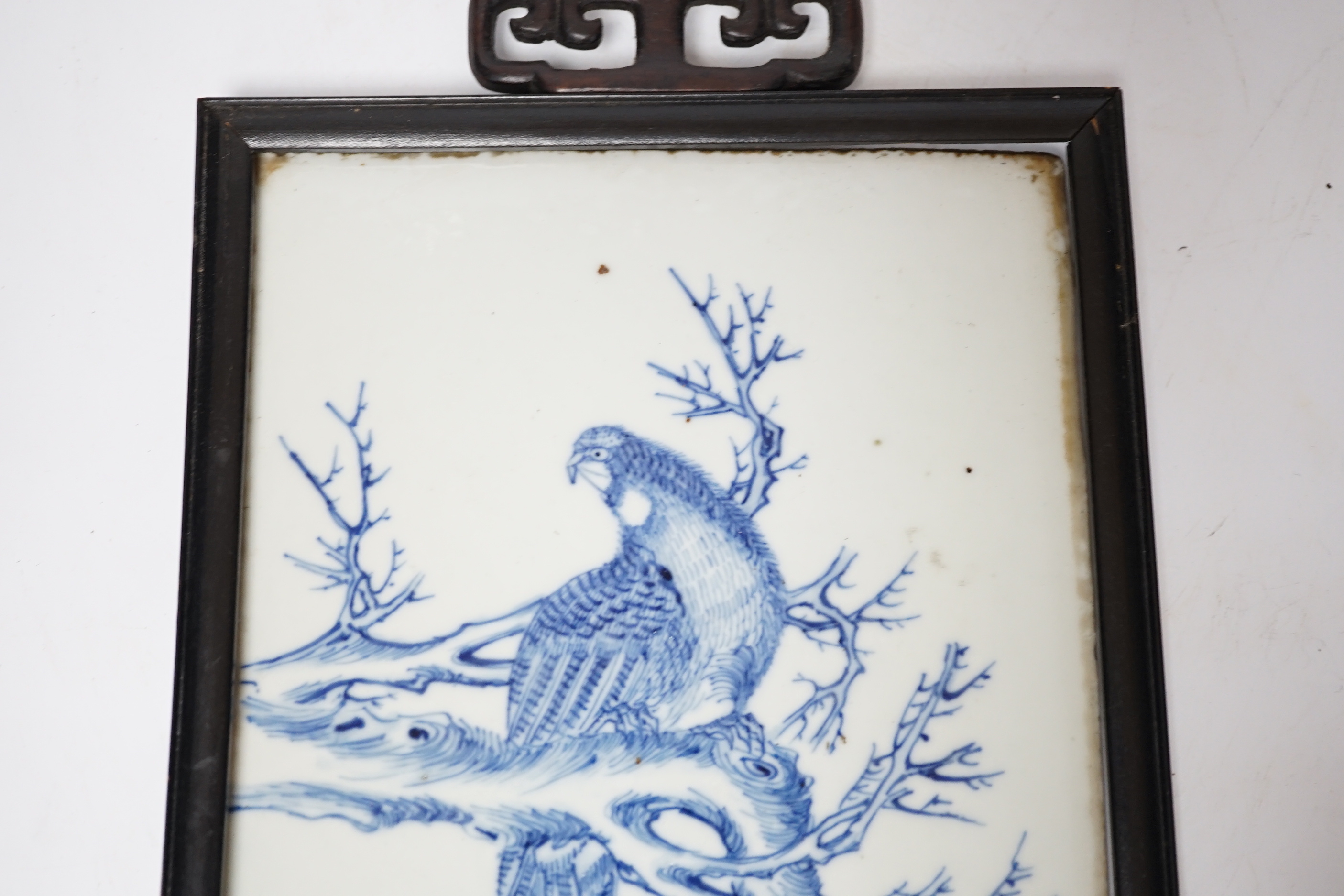 A late 19th century Chinese blue and white plaque of a bird, ebonised frame, 19cm wide x 30cm high including frame